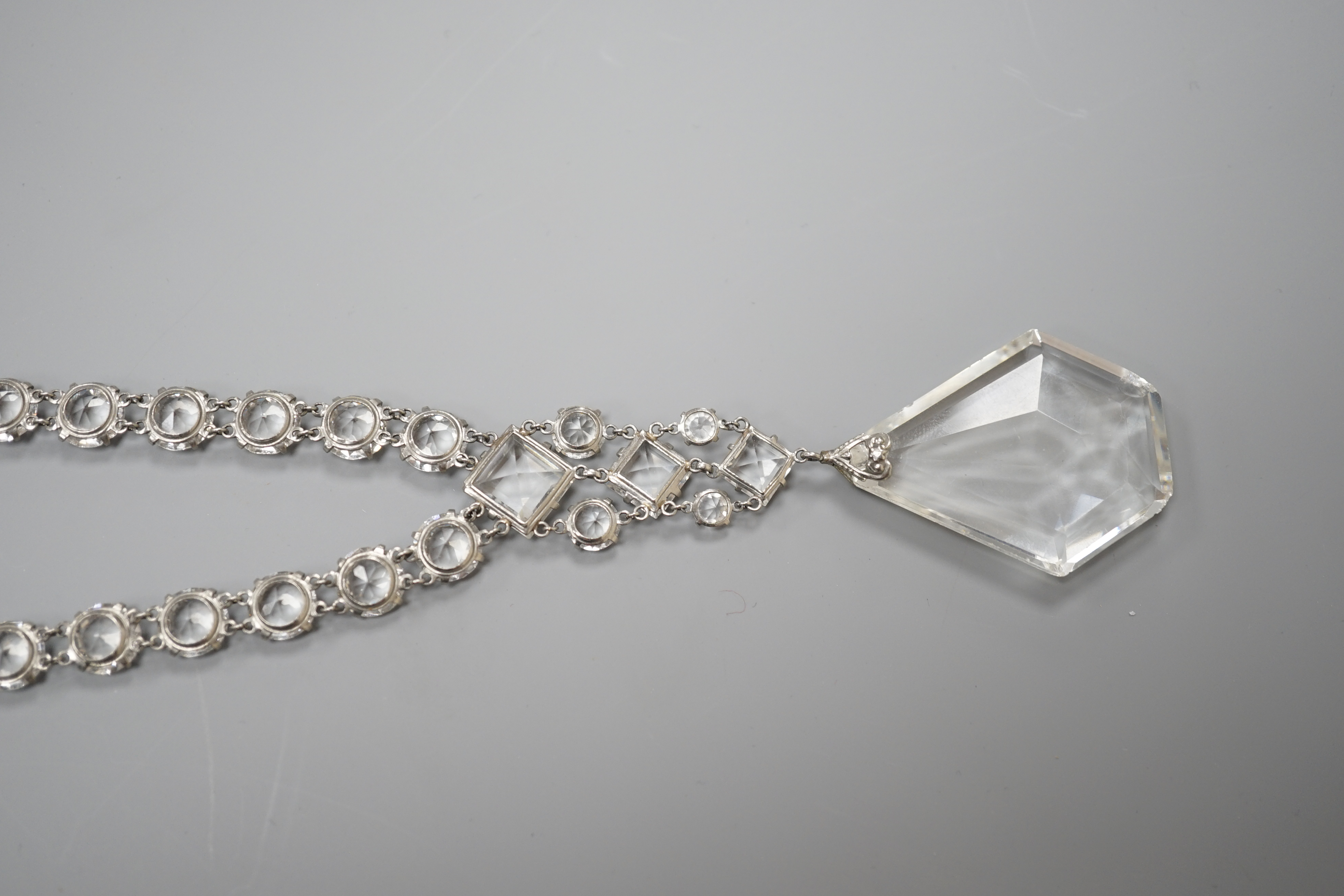 An early 20th century ornate white metal and facet cut paste set drop necklace, overall approx. 44cm.